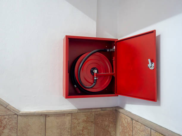 Wall mounted fire water hoses and fire fighting equipment on red cabinet
